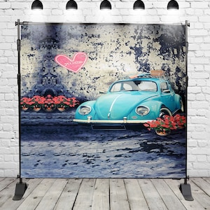 Può includere: Un Volkswagen Beetle blu vintage con una tavola da surf sul tetto, parcheggiato davanti a un muro di mattoni consumato con un cuore rosa che dice "You & Me".