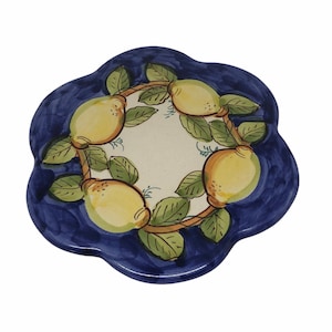 May include: A blue and white ceramic trivet with a lemon design. The trivet is shaped like a flower with five petals. The lemons are yellow with green leaves.
