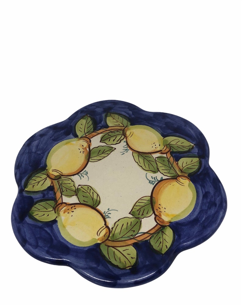 May include: A blue ceramic trivet with a white center and a design of lemons and leaves. The lemons are yellow with green leaves and brown branches.