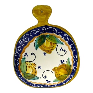 Puede incluir: Un bol de cerámica amarillo con asa, decorado con un borde azul y blanco y un motivo de limón. El bol está pintado a mano con limones amarillos, hojas verdes y espirales azules.