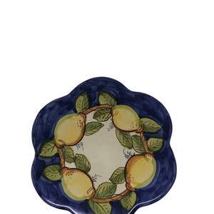 May include: A blue and white ceramic coaster with a design of lemons on a vine. The lemons are yellow with green leaves.