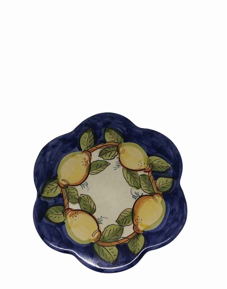 May include: A blue and white ceramic coaster with a design of lemons on a vine. The lemons are yellow with green leaves.