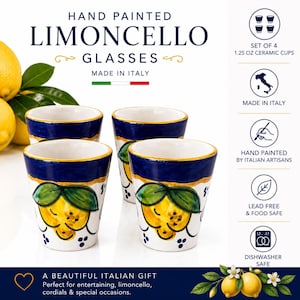 May include: Set of four hand-painted ceramic Limoncello glasses. Each glass features a white base with a yellow lemon design, blue rim, and gold accents. The glasses are 1.25 oz and made in Italy.