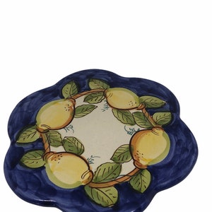 May include: A blue ceramic trivet with a white center and a design of lemons and leaves. The lemons are yellow with green leaves and brown branches.