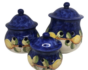 Peut inclure: Ensemble de trois pots à ail en céramique. Les couvercles et les corps sont bleus, décorés de citrons jaunes et de feuilles vertes. Chaque pot est percé de trous d'aération. Trois tailles différentes sont incluses.