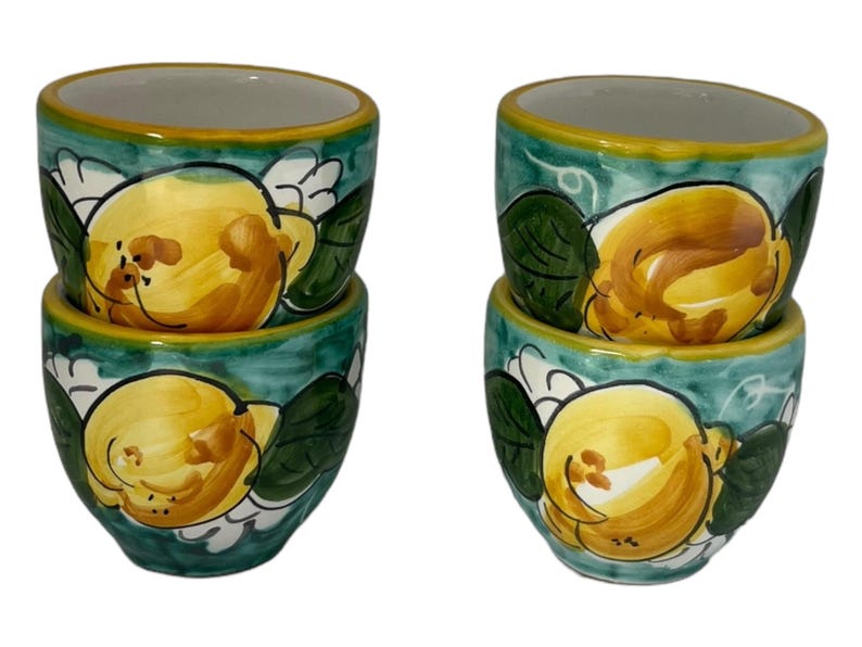 Puede incluir: Juego de cuatro tazas de espresso de cer&aacute;mica con un dise&ntilde;o de lim&oacute;n verde y amarillo. Las tazas est&aacute;n apiladas en pares.