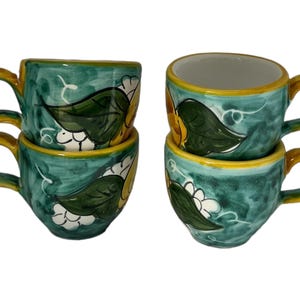 Puede incluir: Juego de cuatro tazas de espresso de cer&aacute;mica verde con dise&ntilde;os florales amarillos y blancos.