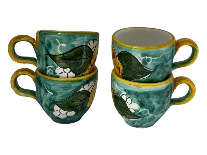 Puede incluir: Juego de cuatro tazas de espresso de cer&aacute;mica verde con dise&ntilde;os florales amarillos y blancos.