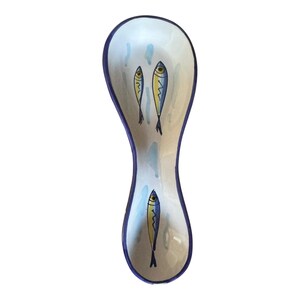 May include: A ceramic spoon rest with a white interior and a blue rim. The spoon rest is decorated with three stylized fish in yellow and blue, with blue water droplet accents.