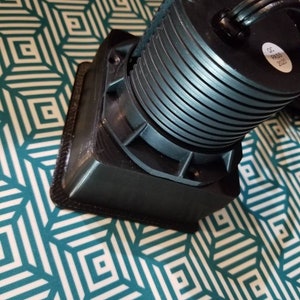 May include: A black, round, electrical device with a series of concentric rings. The device has a black cord and a label that reads "QC PASS 2020".
