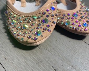 May include: A pair of nude-colored dance shoes with a strap and rhinestones.