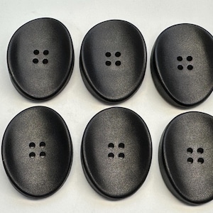 Puede incluir: Seis botones negros ovalados, cada uno con cuatro agujeros. Los botones tienen una superficie texturizada y un acabado mate. Ideales para proyectos de costura y ropa. Miden unos 3 cm de largo.