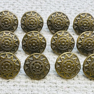 May include: A collection of twelve antique brass cabinet knobs. Each knob features a sunburst design with a central circle and radiating points. The knobs have a vintage, aged appearance, and are round in shape. The knobs are made of brass.