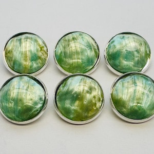 May include: Six round buttons with a silver-colored rim. The button faces have a marbled appearance with shades of green, yellow, and blue. The buttons are arranged in two rows of three.
