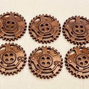 May include: Six bronze-colored steampunk gears with intricate designs. Each gear features a central cogwheel surrounded by a circular frame with smaller gears and decorative elements. The gears are arranged in two rows of three.