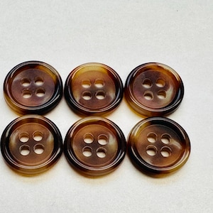 May include: Six brown plastic buttons with four holes each. The buttons have a mottled pattern.