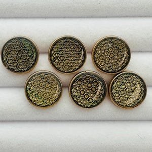 May include: Six round, gold-colored buttons with a green and gold geometric design. The buttons are arranged in a semi-circle.