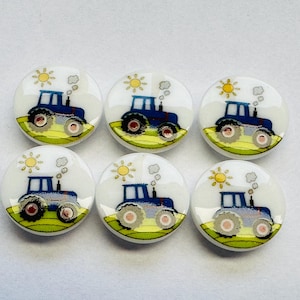 May include: Six round, white buttons featuring a blue tractor design. Each button shows a blue tractor on a green field, with a yellow sun and white clouds. The tractor has red and grey wheels.
