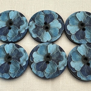 Könnte beinhalten: Sechs runde Knöpfe mit einem floralen Design in Jeansoptik. Jeder Knopf hat einen dunkelblauen Hintergrund mit einem hellblauen Blumenmuster. Die Knöpfe haben zwei Löcher zum Nähen und sind in einem Raster angeordnet.