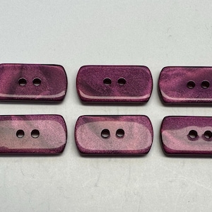 May include: Six rectangular buttons with rounded corners. The buttons are a deep, shimmering purple with two holes each. The buttons are arranged in two rows of three.
