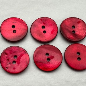May include: Six red, round, two-hole buttons made of mother of pearl.