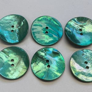 Puede incluir: Seis botones redondos verdes iridiscentes, cada uno con dos o cuatro agujeros. Los botones tienen un aspecto arremolinado y veteado con tonos de verde esmeralda y turquesa. Estos botones decorativos son adecuados para proyectos de costura y manualidades.