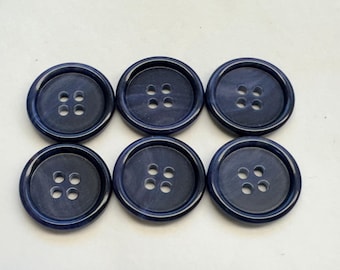 May include: Six dark blue plastic buttons with four holes each. The buttons have a marbled effect.