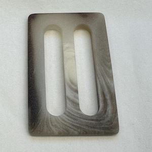 May include: A brown and white marbled plastic buckle with two slots.
