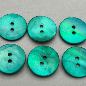 Può includere: Sei bottoni rotondi, verde acqua iridescenti, ciascuno con due fori. I bottoni hanno una lucentezza perlacea, che riflette sfumature di verde e blu. Adatti per cucito e progetti di artigianato.