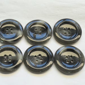 May include: Six black and white buttons with four holes each. The buttons are round and have a glossy finish.