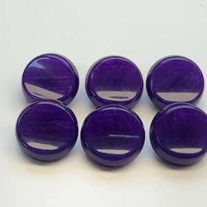 Peut inclure: Six pierres rondes et polies de couleur violette sont disposées sur une surface blanche. Les pierres ont une finition brillante et un aspect marbré, avec des stries violettes plus claires. Les objets sont espacés uniformément.