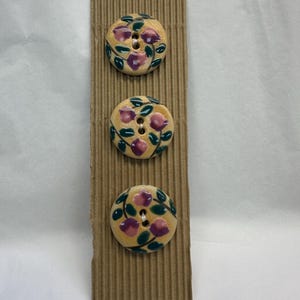 Keramische knopen 32 mm met een gestileerd paars en groen bloemontwerp van Incomparable Buttons, verkocht als kaart met drie knopen