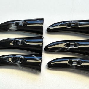 以下が含まれることがあります： 大理石模様の白い模様が入った、光沢のある黒いトグルボタン6個。 各ボタンには縫い付け用の穴が2つあります。 ボタンは湾曲しており、先端は丸みを帯びています。