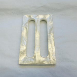 Puede incluir: Portaplumas rectangular blanco con dos ranuras para bolígrafos. El portaplumas está hecho de un material marmoleado.