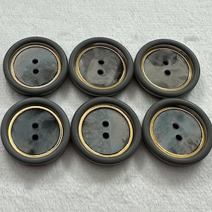 May include: Six grey buttons with a gold rim and two holes. The buttons have a marbled pattern.