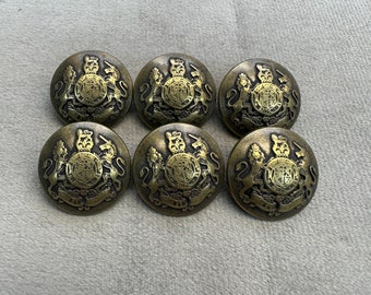 May include: Six gold-toned metal buttons with a detailed design featuring a crown and lions. The buttons are round and have a raised design.