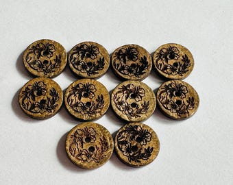 May include: Ten round wooden buttons with a floral design etched into the surface. The buttons are light brown with dark brown etched details. Each button has two holes for sewing.
