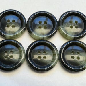 Puede incluir: Seis botones negros y verdes con espiral y cuatro agujeros cada uno.