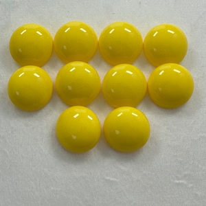 May include: Ten bright yellow round cabochons, likely for jewellery making or crafting.