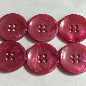 Bright pink buttons, 28mm pearlised finish, four-hole, sew-through design. Sold as a set of six buttons. Knitwear, fashion, projects.