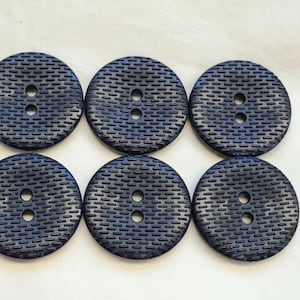 May include: Six navy blue, round buttons with a textured surface and two holes each. The buttons are arranged in two rows of three, showcasing their consistent design and colour. These buttons are suitable for various sewing projects.