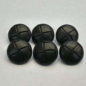 Peut inclure: Six boutons ronds noirs avec un aspect cuir tressé. Les boutons sont espacés uniformément sur un fond blanc. Ces boutons conviennent à divers projets de couture et d'artisanat.