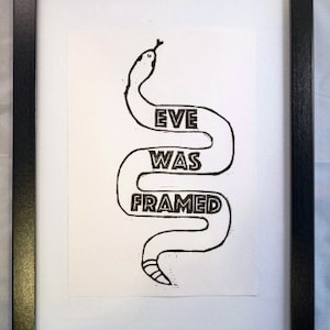 May include: A black and white illustration of a snake with the words "Eve Was Framed" written on its body.