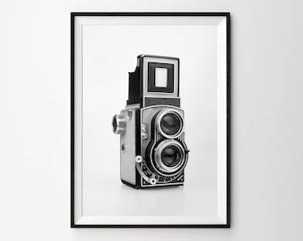 May include: A black and silver vintage camera with two lenses. The camera is on a white background.