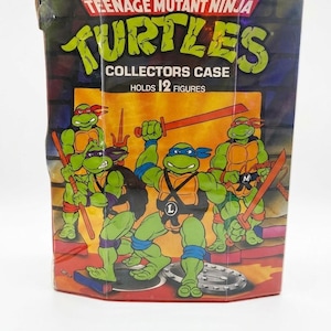 May include: A Teenage Mutant Ninja Turtles collectors case with a red border and a graphic of four green turtles in action poses. The text reads Teenage Mutant Ninja Turtles Collectors Case Holds 12 Figures. The case features a brick wall background.