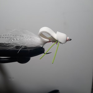 May include: White fly fishing lure with a foam body and green and red accents.
