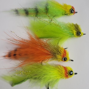 May include: Four fly fishing lures with yellow, orange, and green feathers. The lures have black eyes and red accents.