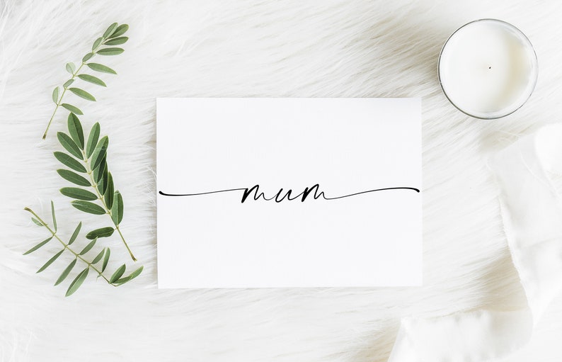 May include: A white card with the word "mum" written in black cursive script on a white background.