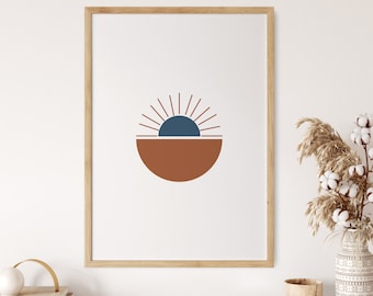 May include: A framed print featuring a minimalist geometric design of a sun with a blue centre and a brown semi-circle beneath. The print is on a white background and is framed in a light wood frame.