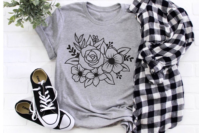 May include: A gray t-shirt with a black floral design featuring a rose and other flowers.
